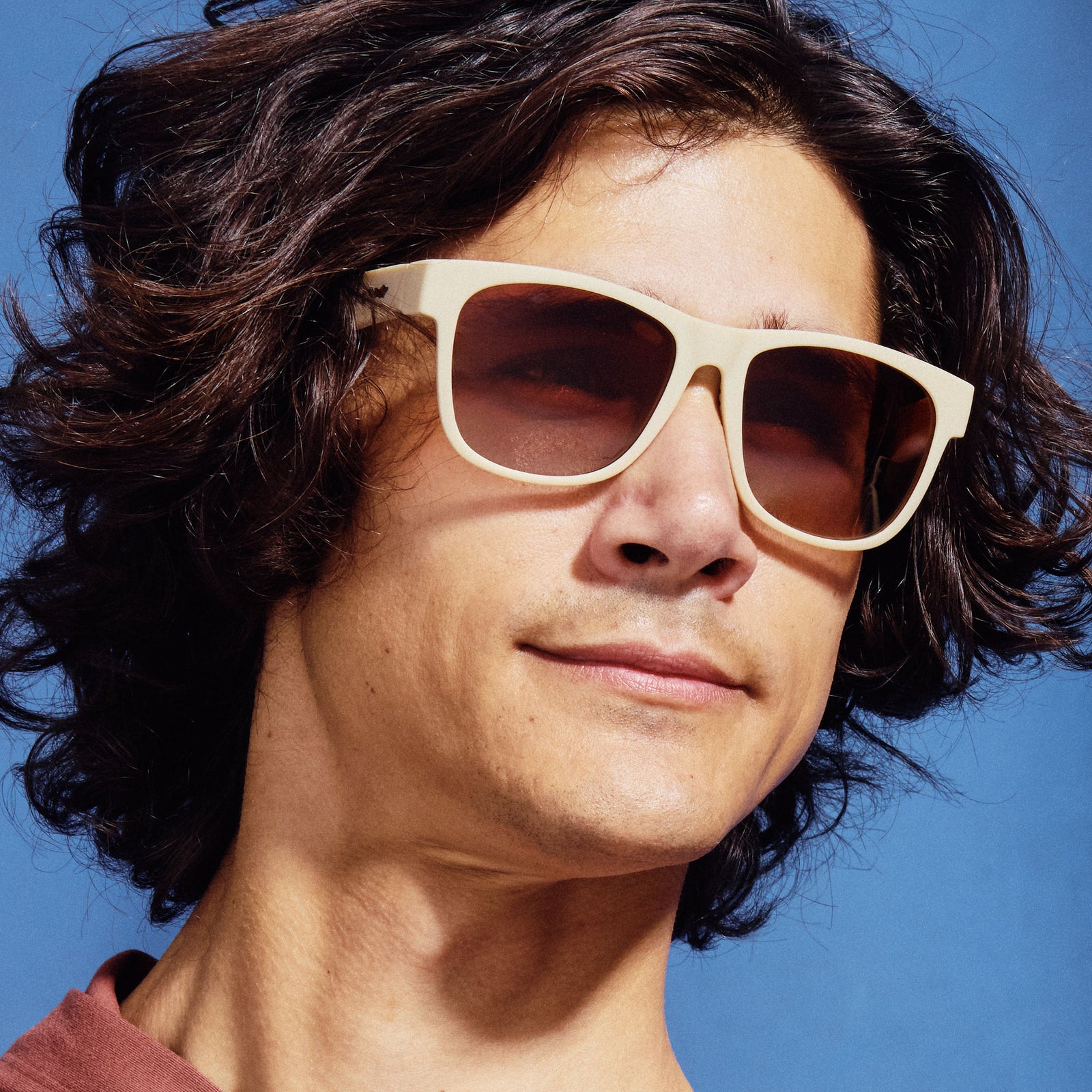 A man wearing cream-colored, square shaped sunglasses.