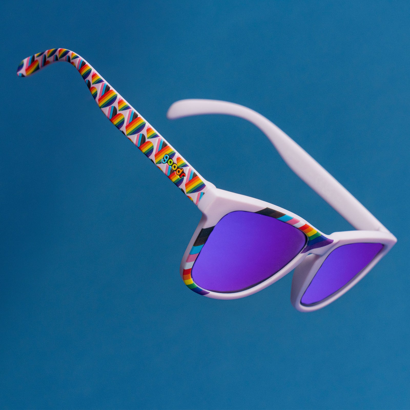 Three-quarter angle view of lilac rainbow flag LGBTQ+ Pride sunglasses with purple lenses hovering mid-air facing down.